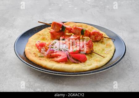 Lo shashlik servito su tortilla con pomodoro e cipolla rossa Foto Stock