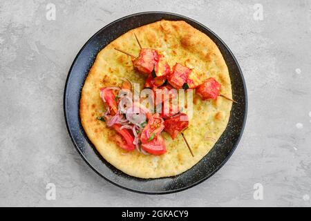 Vista dall'alto dello shashlik servito su tortilla con pomodoro e cipolla rossa Foto Stock