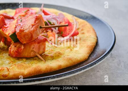 Primo piano di shashlik servito su tortilla con pomodoro e cipolla rossa Foto Stock