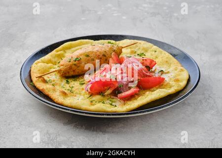 Kebab servito su tortilla con pomodoro e cipolla rossa Foto Stock