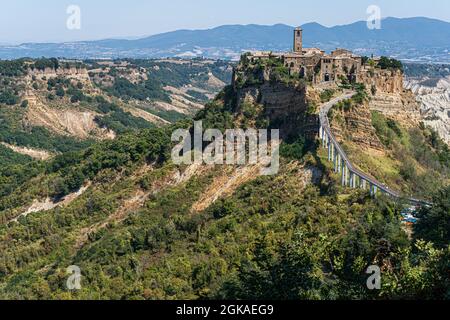 VITERBO ITALIA, REGNO UNITO. 13 Settembre 2021. I turisti camminano sul ponte per Civita di Bagnoregio, un pittoresco villaggio collinare in Italia, è una popolare destinazione di un giorno da Roma in una giornata calda. Il turismo italiano ha raggiunto un picco inestimabile nei mesi di luglio e agosto, poiché secondo la Confederazione Italiana del mestiere e delle piccole e medie imprese (CNA) con l’aumento della domanda di viaggi è stato attribuito all’attuazione del green pass del paese. Credit: amer Ghazzal/Alamy Live News Foto Stock