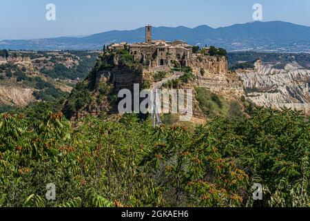 VITERBO ITALIA, REGNO UNITO. 13 Settembre 2021. I turisti camminano sul ponte per Civita di Bagnoregio, un pittoresco villaggio collinare in Italia, è una popolare destinazione di un giorno da Roma in una giornata calda. Il turismo italiano ha raggiunto un picco inestimabile nei mesi di luglio e agosto, poiché secondo la Confederazione Italiana del mestiere e delle piccole e medie imprese (CNA) con l’aumento della domanda di viaggi è stato attribuito all’attuazione del green pass del paese. Credit: amer Ghazzal/Alamy Live News Foto Stock