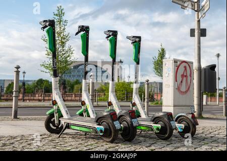 Una fila di quattro Scooter elettrici in piedi o e-scooters dalla società CALCE sul marciapiede a Berlino Foto Stock