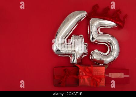 Palloncini argentati 45 quarantacinque in corona su sfondo rosso scuro. Decorazione festa di festa, 40 concetto di cartolina con vista dall'alto Foto Stock