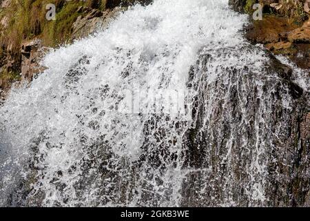 Primo piano di una potente cascata di alta qualità. Vista laterale di una cascata soleggiato nella natura selvaggia. Un grande flusso d'acqua si riversa verso il basso dal monte Foto Stock