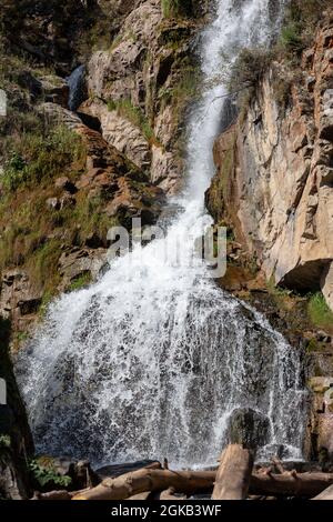 Primo piano di una potente cascata di alta qualità. Vista laterale di una cascata soleggiato nella natura selvaggia. Un grande flusso d'acqua si riversa verso il basso dal monte Foto Stock