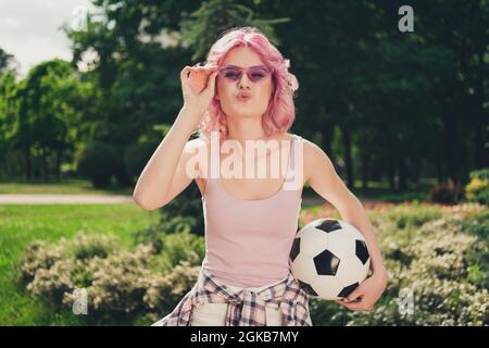 Foto di giovane sportivo ragazza felice sorriso positivo pointed labbra inviare aria bacio flirty tenere il gioco di calcio all'aperto Foto Stock