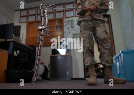 Senior Airman Trevon Robinson, uno specialista di gestione di peste, pratica la manipolazione di serpenti con un python palla presso l'edificio di base Pest Management, 4 marzo 2021, presso la base aerea di Kadena, Giappone. I tecnici del 18° ingegnere civile Squadron per la gestione dei parassiti sono responsabili della rimozione, del trasferimento e dello sterminio di specie invasive, parassiti e insetti in tutte le basi di Okinawa. Foto Stock