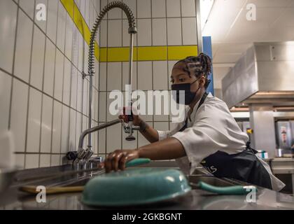 US Air Force Airman 1st Class Christina Cashaw-Williams, 786th Force Support Squadron fitness Technician, lava i piatti durante una gara di cook-off alla Kapaun Air Station, Germania, 4 marzo 2021. Due squadre composte da sei e sette Airmen del 786° FSS gareggiavano l'una contro l'altra in un cuoco-off di tre portate vincitore-take-all. Foto Stock