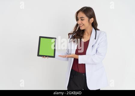 un medico femminile con un gesto che presenta qualcosa mentre mostra lo schermo di un pad alla fotocamera Foto Stock