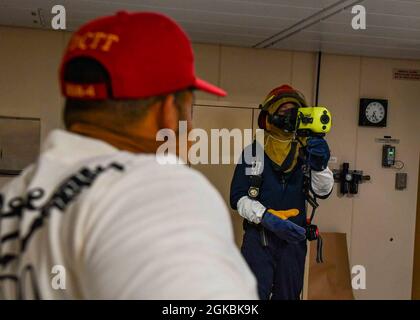 OCEANO ATLANTICO (Mar. 05, 2021) Chief Aviation Boatswain’s Mate (Aircraft Handling) Hector Amador, a sinistra, un membro del DCTT (Damage Control Training Team), osserva Aviation Support Equipment Technician di seconda classe John Fazio utilizzare una termocamera Naval Firefighting Thermal Imager (NFTI) durante una trivella antincendio a bordo della base navale USS Hershel “Woody” Williams (ESB 4) nell'Oceano Atlantico, 05 marzo 2021. Hershel “Woody” Williams opera nella Sixth Fleet statunitense per condurre una formazione di interoperabilità e costruire partnership strategiche con i partner africani. Foto Stock