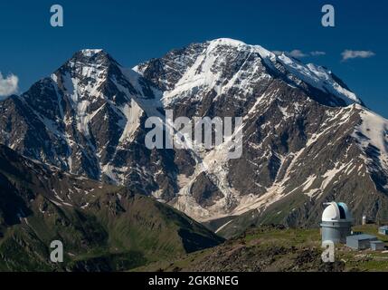 Osservatorio nelle montagne del Caucaso. Osservatorio astronomico sullo sfondo delle montagne innevate. Bellissimo paesaggio di montagna in giornata estiva soleggiata Foto Stock