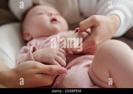 Mani di giovane madre calmando il bambino carino giù mentre lulling lei dopo l'alimentazione Foto Stock