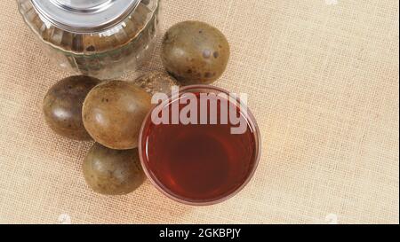 Monk frutta o Luo Han Guo. Frutta secca per una sana bevanda dolcificante. Rimedio naturale alle erbe e sfondo bottiglia di vetro. Mistico bevanda di frutta per chi conce Foto Stock