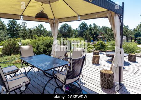 Patio con tavolo da pranzo e sedie sotto la tettoia e area barbecue nella tenuta di campagna Foto Stock