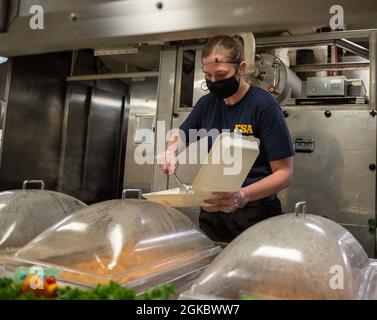 Aviation Structural Mechanic 3rd Class Katelyn Parsons, di San Angelo, Texas, assegnato al reparto di approvvigionamento della USS Gerald R. Ford (CVN 78), serve cibo nella cucina poppiera della Ford, 7 marzo 2021. Ford è in corso nell'Oceano Atlantico conducendo un evento indipendente di vaporizzazione. Foto Stock