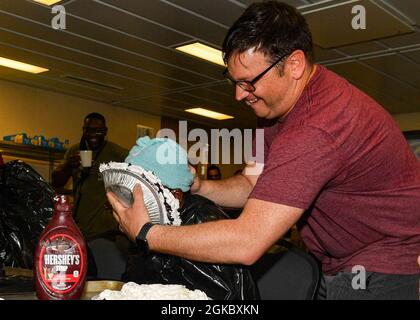 OCEANO ATLANTICO (Mar. 07, 2021) Damage Controlman 1st Class Jacob Tuggle preme una torta sul volto di Machinist Mate 1st Class Temidayo Olayinka durante un evento di raccolta fondi della First Class Petty Officer Association (FCPOA) a bordo della base navale di Expeditionary Sea base USS Hershel “Woody” Williams (ESB 4) nell'Oceano Atlantico, marzo 07, 2021. Hershel “Woody” Williams opera nella Sixth Fleet statunitense per condurre una formazione di interoperabilità e costruire partnership strategiche con i partner africani. Foto Stock