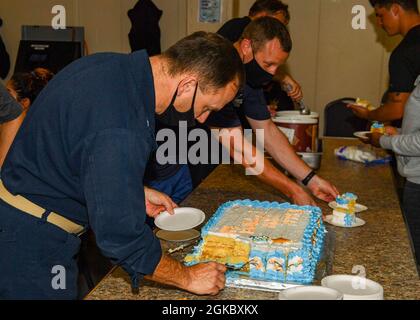 OCEANO ATLANTICO (Mar. 07, 2021) Comandante ufficiale, Capt. Michael Concannon, a sinistra, serve torta per l'anniversario delle navi commissionate a bordo della base del mare di Expeditionary USS Hershel “Woody” Williams (ESB 4) nell'Oceano Atlantico, 07 marzo 2021. Hershel “Woody” Williams opera nella Sixth Fleet statunitense per condurre una formazione di interoperabilità e costruire partnership strategiche con i partner africani. Foto Stock