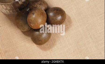 Monk frutta o Luo Han Guo. Frutta secca per una sana bevanda dolcificante. Rimedio naturale alle erbe e sfondo bottiglia di vetro. Mistico bevanda di frutta per chi conce Foto Stock