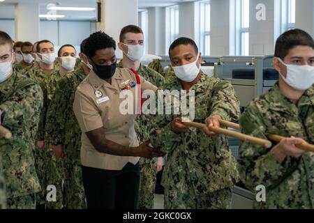 Aviation Machinist's Mate 1st Class Latasha Lawrence, un comandante della divisione di reclutamento, corregge il posizionamento del braccio di una guida di reclutamento durante la pratica di perforazione all'interno di un compartimento delle caserme di reclutamento USS Triton al comando di addestramento di reclutamento. Più di 40,000 reclute si allenano ogni anno presso l’unico campo di stivali della Marina. Foto Stock