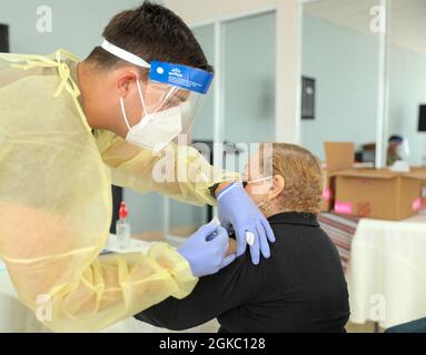 PFC. Michael Colón, un medico della Guardia Nazionale di Porto Rico, vaccina uno dei residenti all'Egida del Policía a Trujillo Alto, Porto Rico, 8 marzo 2021. Soldati e Airmen assegnati alla Task Force congiunta - Porto Rico continuano il loro impegno senza fine per vaccinare ogni cittadino anziano dell'isola. Foto Stock