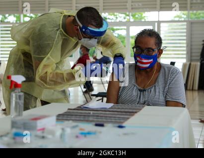 SPC. Rolando Santiago, un medico della Guardia Nazionale di Porto Rico, vaccina un residente all'Egida del Policía a Trujillo Alto, Porto Rico, 8 marzo 2021. Soldati e Airmen assegnati alla Task Force congiunta - Porto Rico continuano il loro impegno senza fine per vaccinare ogni cittadino anziano dell'isola. Foto Stock