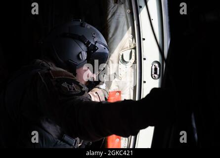 Personale Sgt. Lauren Shaw, 36esimo loadmaster Airlift Squadron, guarda fuori una porta laterale di un C-130J Super Hercules C-130J Super Hercules assegnato al 36esimo Squadron Airlift durante un esercizio Airborne 21, sopra il Combined Arms Training Center Camp Fuji, Giappone, 9 marzo 2021. I Loadmasters assicurano che le configurazioni degli aerei siano corrette e adeguatamente preparate per i paracadutisti a saltare, così come noi maneggiamo ogni procedura di emergenza che può verificarsi durante le operazioni di caduta. Foto Stock