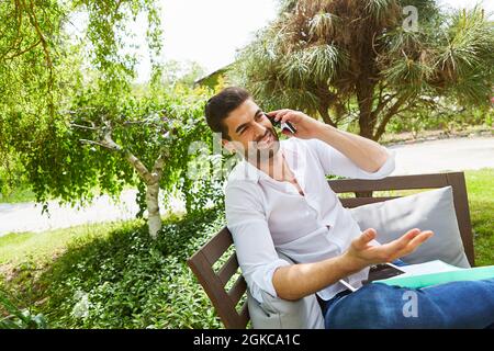 Giovane come freelance in vacanza in estate parlando al telefono con lo smartphone Foto Stock