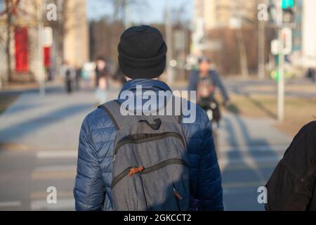 Un ragazzo con uno zaino dalla parte posteriore. Un uomo con un cappello e uno zaino. Una persona sconosciuta cammina attraverso la città. Foto Stock