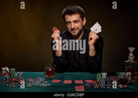 Uomo giocatore di casinò bearded che gioca a poker su tavolo verde Foto Stock