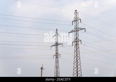 Supporta linee di alimentazione ad alta tensione contro il cielo. Industria elettrica in Europa. Foto Stock