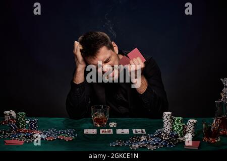 Uomo giocatore di casinò bearded che gioca a poker su tavolo verde Foto Stock