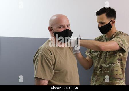 Esercito degli Stati Uniti Sgt. Il Major Guy Miller, specialista di manutenzione dell'aviazione con la 28a brigata dell'aviazione di combattimento di Expeditionary, riceve un vaccino COVID-19 da Sgt. Kenneth Hesler, medaglia di combattimento con la 156a squadra di combattimento di Brigade di fanteria, in una clinica medica nell'area operativa del 28esimo ECAB in Medio Oriente. Il vaccino Johnson & Johnson Janssen COVID-19 richiedeva un solo colpo. Dopo aver ricevuto il vaccino, i soldati sono stati monitorati per 15 minuti dal personale medico. Foto Stock