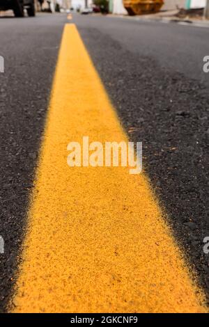 Pista asfaltata appena realizzata con un po' di sporco e la sua consistenza, con una striscia gialla dipinta al centro dell'immagine e sopra l'orizzonte stradale Foto Stock