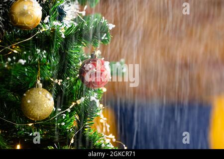 Composizione della neve che cade sull'albero di natale con baubles su sfondo sfocato Foto Stock