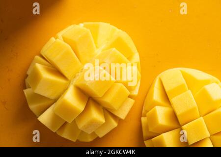 Mango tagliato a metà su sfondo giallo, vista dall'alto Foto Stock