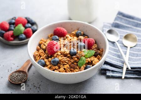 Ciotola di granola di avena fatta in casa con bacche su fondo di tavola di cemento. Cereali sani per la colazione, cibi sani per la dieta Foto Stock