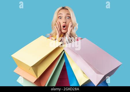 Addetta molto contentata seduta con borse per lo shopping in studio Foto Stock