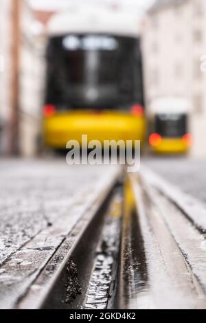 Due tram nella sfocatura al capolinea con focalizzazione sulla rotaia anteriore Foto Stock