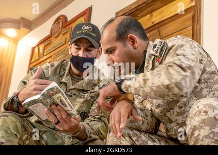 Task Force Spartan Soldier, U.S. Army Sgt. 1a Classe Davin Schultz, un 36esimo sparatutto della Divisione di fanteria di Manor, Texas, confronta le guide tascabili con il comandante delle forze Armate giordane della Unit Tank Company del 3rd Border Guard Group, CPT. Salem Abu Nwaer, 17 marzo 2021. I soldati TF Spartan della Divisione Tactical- Giordania hanno consigliato e assistito i soldati del 3° gruppo di Guardia di confine attraverso la condivisione delle conoscenze di base delle abilità soldato e la dimostrazione di tattiche di squadra piccola. Le opportunità di condividere abilità e abilità con le nostre nazioni partner rafforzano ulteriormente i rapporti e. Foto Stock