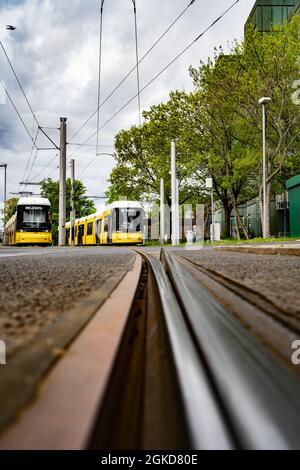 Due tram nella sfocatura al capolinea con focalizzazione sulla rotaia anteriore Foto Stock