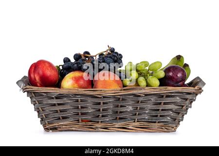 Cestino di frutta intrecciato con una varietà di frutta in esso. Isolato su sfondo bianco. Foto Stock