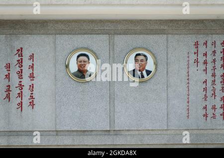 Ritratti di Kim Ll-Sung e Kim Jong adornano ogni treno stazione ferroviaria in Corea del Nord. Spesso con le citazioni della loro saggezza accanto a loro. Foto Stock