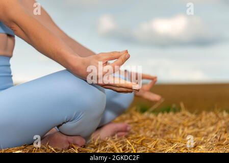 primo piano di una donna che pratica lo yoga all'esterno in un campo, meditazione e concetto di spazio di testa. Foto Stock