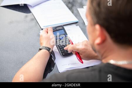 Fischbach, Germania. 13 settembre 2021. Un uomo è seduto a casa in giardino lavorando sulla sua calcolatrice. Credit: Silas Stein/dpa/Alamy Live News Foto Stock