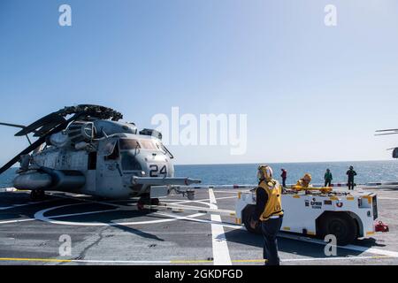 OCEANO PACIFICO (20 marzo 2021) — Ensign Peter Obeng, Operations Intelligence Division Officer, e Aviation Boatswain’s Mate (Handler) 2a classe Evelyn Martin del campo Garcia, da Riverside, Calif., traina un elicottero CH-53E Super Stallion attraverso il ponte di volo del molo di trasporto anfibio di classe San Antonio USS Portland (LPD 27). Portland sta conducendo operazioni di routine nella terza flotta degli Stati Uniti. Foto Stock