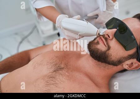 Ragazzo giovane in occhiali protettivi durante una procedura cosmetica Foto Stock