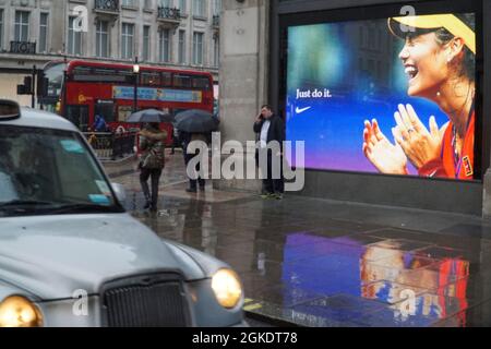 Londra, UK, 14 settembre 2021: A Nike Town a Oxford Circus nel cuore del West End, i giganteschi schermi mostrano immagini del prodigio del tennis Emma Raducanu, scattata un momento dopo aver vinto il torneo di tennis US Open. Emma Raducanu è sponsorizzato da Nike e si prevede di poter costruire una carriera lucrativa con sponsorizzazioni e approvazioni commerciali grazie alla sua straordinaria capacità sportiva combinata con un buon look, giovani e fascino multiculturale sulla base del suo patrimonio congiunto rumeno e cinese. Anna Watson/Alamy Live News Foto Stock