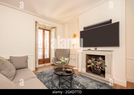 Soggiorno con divano, tavolino da caffè, camino in marmo e grande TV a schermo piatto e sound bar in un appartamento in affitto per le vacanze Foto Stock