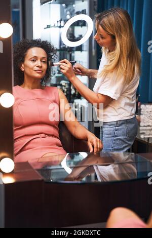Stilista professionale che fa il trucco per il suo cliente Foto Stock